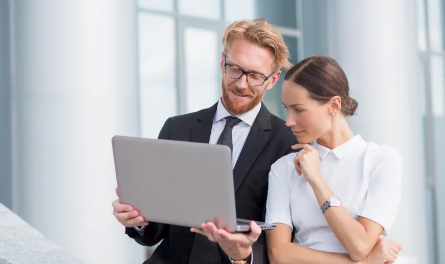 Two people reviewing work together on a laptop as part of a project team