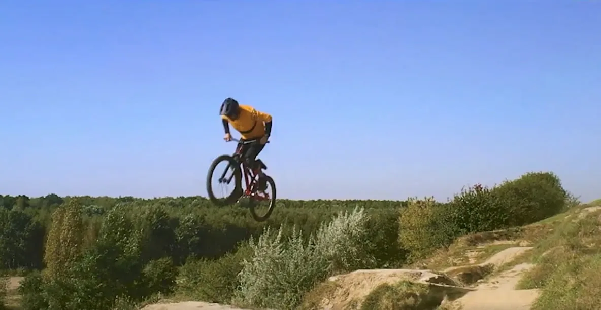 A cyclist jumping on a trail at Bikepark Kazoora, supported by Astrafox