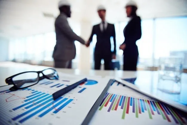 Printed analytics charts on a meeting table while three businesspeople discuss cooperation